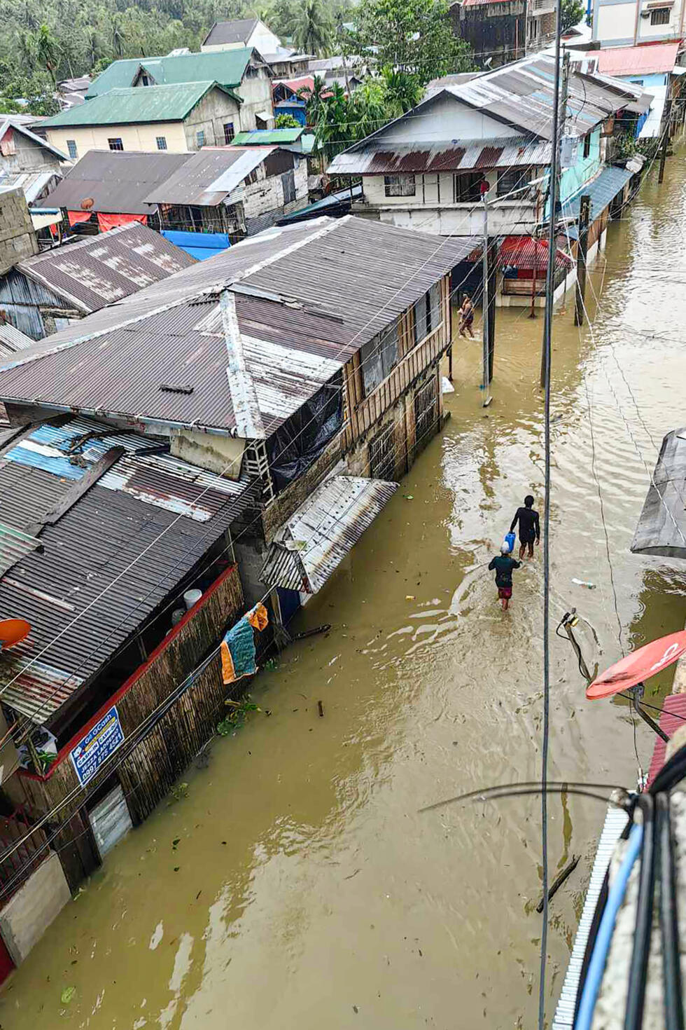A photo taken by Mayor Benjie Ver shows people wading through a flooded street following heavy rains in Jipapad town, Eastern Samar province.