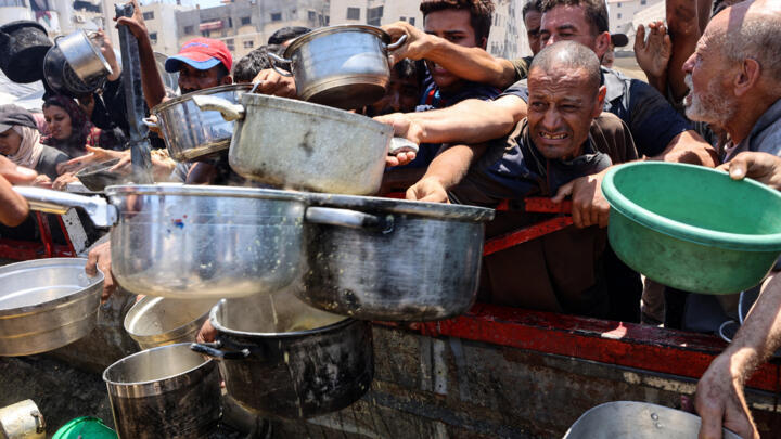 Palestinians gather at a lentil soup distribution point in Gaza City in the northern Gaza Strip on July 27, 2025.