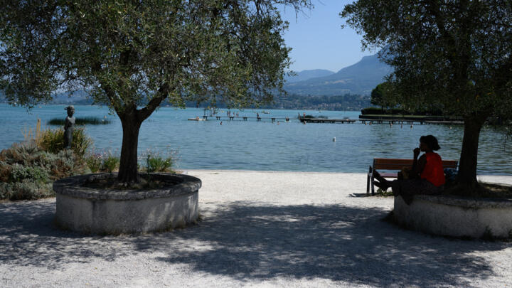 A woman protects herself from the sun along Lake Bourget, in Le Bourget-du-Lac, in the French Alps, on August 8, 2025.