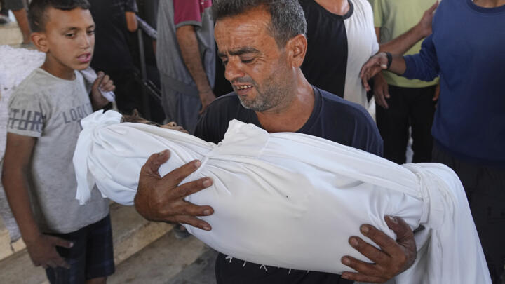 A Palestinian man carries the body of his child who was killed in an Israeli military strike on Gaza, at Al-Shifa Hospital in Gaza City, Thursday, June 19, 2025. 