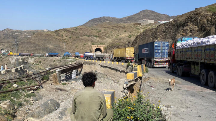 A man sits next to trucks parked at the Torkham border crossing, after Pakistan closed border crossings with Afghanistan, following exchanges of fire between the forces of the two countries, in Torkha