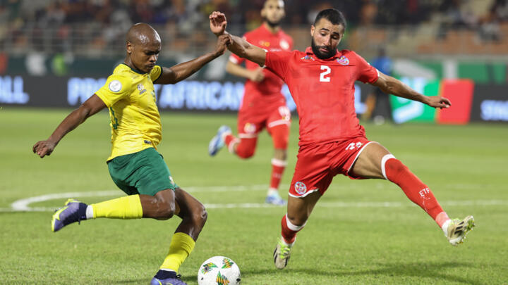 South Africa forward Percy Tau (L) crosses under pressure from Tunisia defender Ali Abdi in their final Group E match in Korhogo, Ivory Coast, on January 24, 2024.