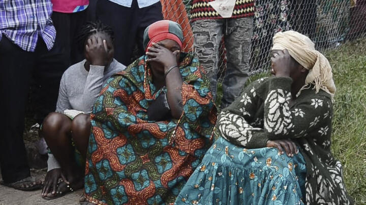 Local residents are seen at the site of an attack at the Mpondwe Lhubiriha Secondary School in Mpondwe, Uganda on June 17, 2023.