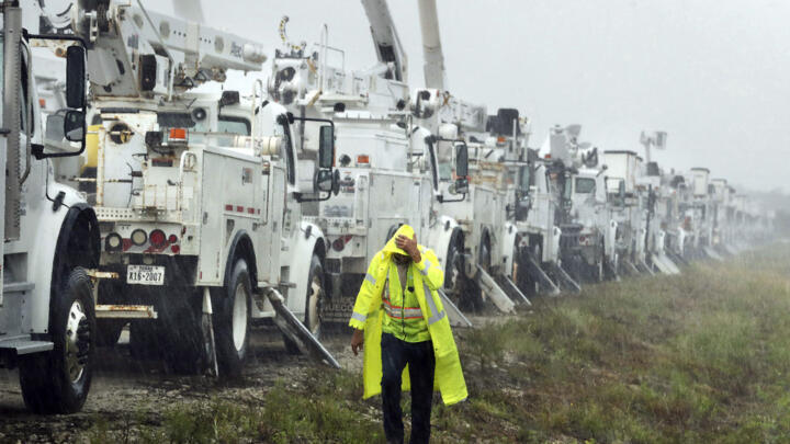 Charles Starling, a lineman with Team Fishel, is pelted with rain as he walks by a row of electrical line trucks staged in a field in The Villages, Florida, on September 26, 2024.