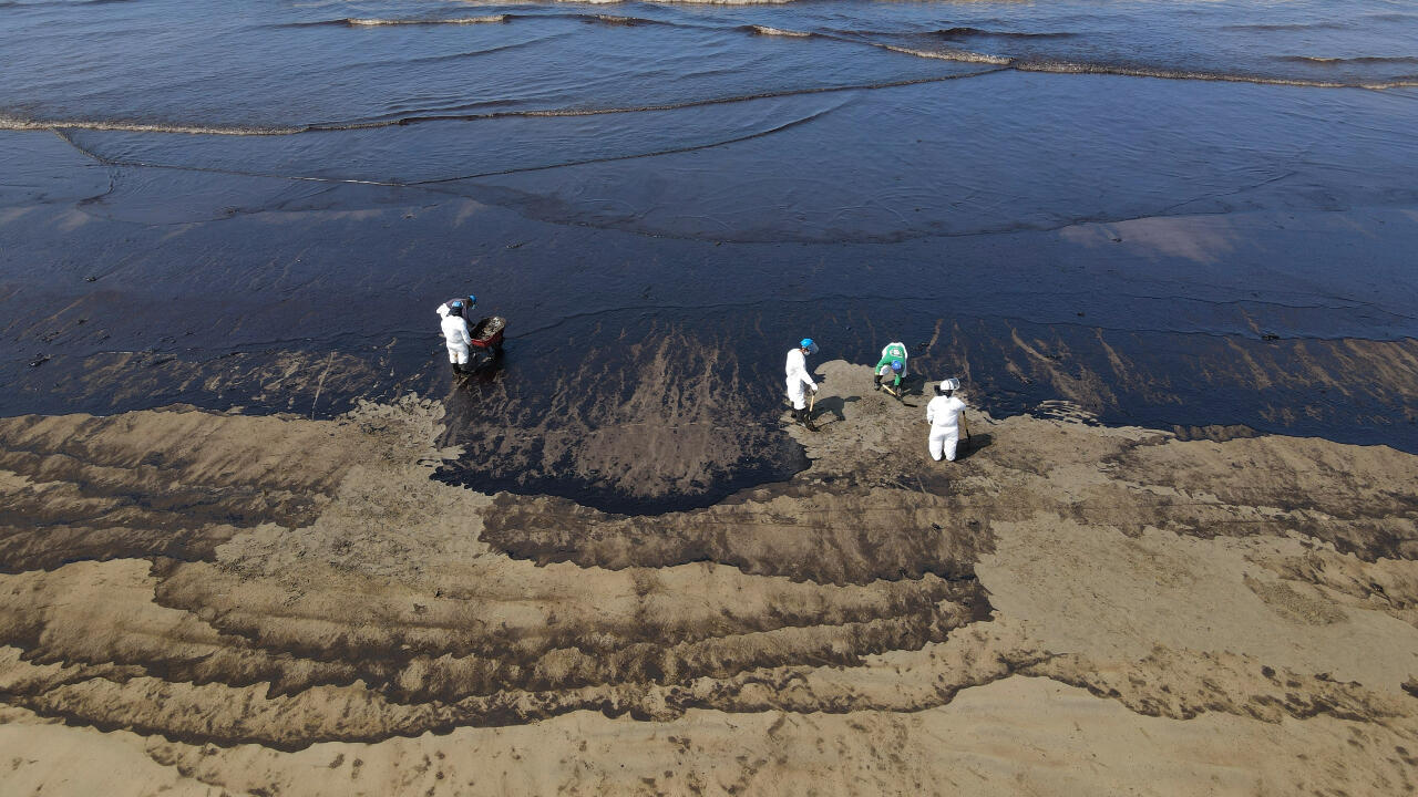 Trabajadores limpian el petróleo derramado en la playa Cavero en Ventanilla, Perú, el 18 de enero de 2022.