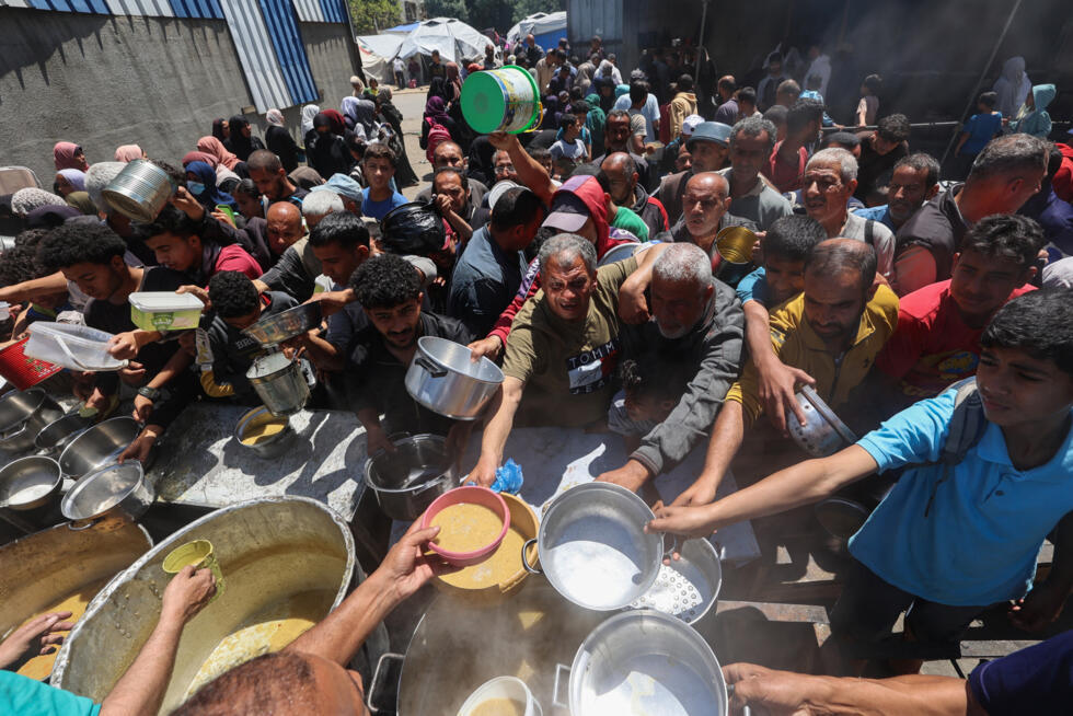 Des Palestiniens font la queue pour un repas chaud dans une cuisine caritative gérée par le Programme alimentaire mondial (PAM) des Nations unies au camp de Nousseirat, à Gaza, le 26 avril 2025.