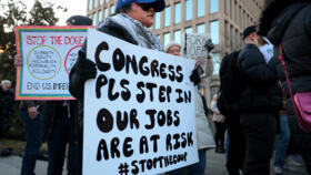 美國聯邦工作人員和支持者在人事管理辦公室 (OPM) 總部外舉著標語，抗議伊隆馬斯克和他的政府效率部 (DOGE)。