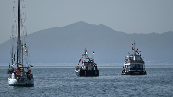 A ship (R), known as the "Family" and is part of the Global Sumud Flotilla, is anchored off the coast of the village of Sidi Bou Said on September 9, 2025.