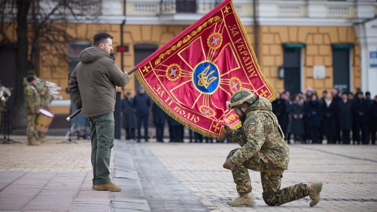 El presidente de Ucrania, Volodímir Zelenski, entrega una bandera a un militar durante una ceremonia dedicada al primer aniversario de la invasión rusa. En Kiev, Ucrania, el 24 de febrero de 2023.