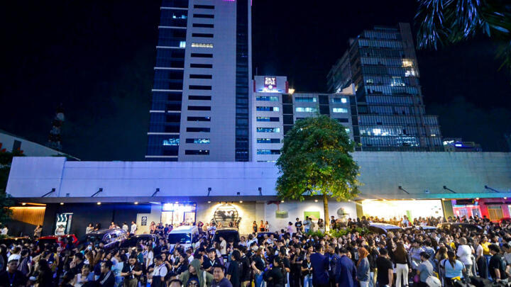 Call center employees surf their mobile phones as they gather outside their office building after the earthquake in Cebu, central Philippines, September 30, 2025.