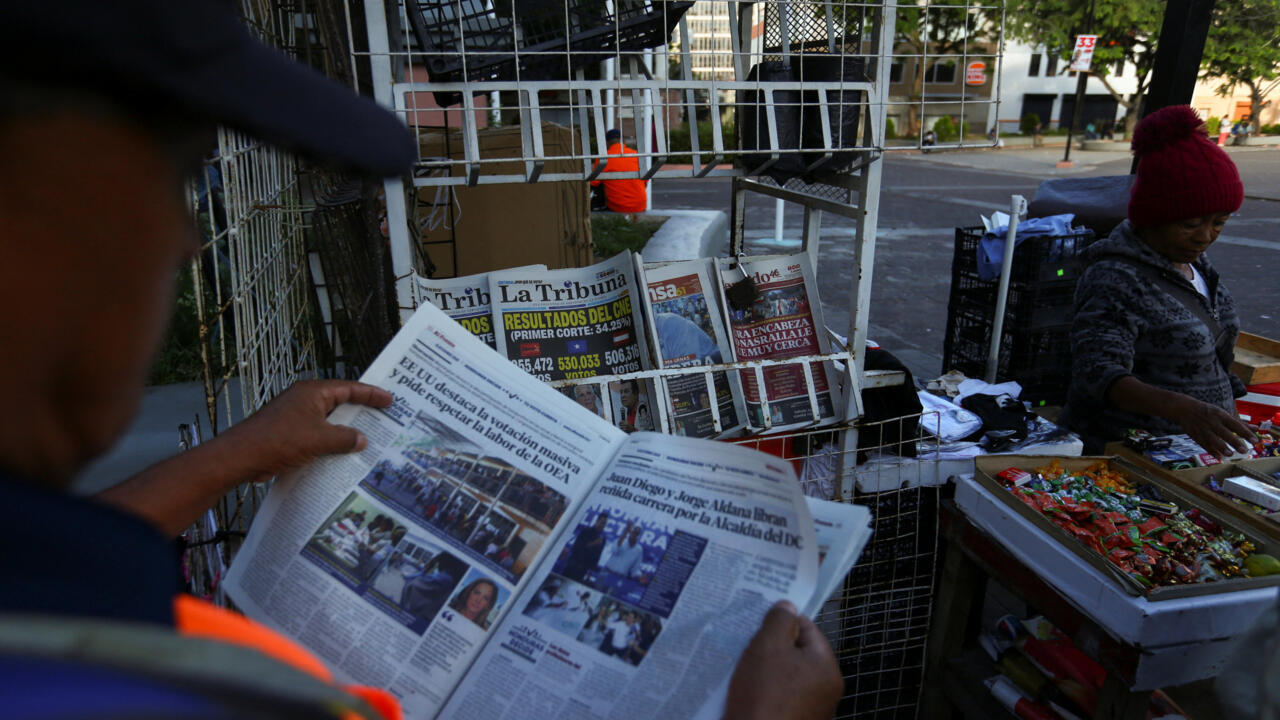 Un hombre lee junto a un quiosco que exhibe artículos de portada sobre los resultados preliminares de las elecciones generales en Tegucigalpa, Honduras, el 1 de diciembre de 2025.