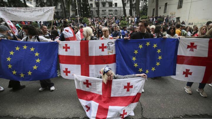 Demonstrators with Georgian national and EU flags gather in front of police during an opposition protest against the foreign influence bill at the Parliamentary building in Tbilisi, Georgia.