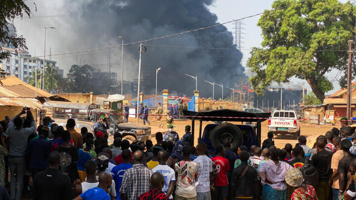 People look at the explosion site from behind the safety barrier after the blast at an oil terminal in Conakry, Guinea December 19, 2023.