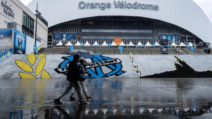 Pedestrians walk past the Velodrome Stadium on a rainy day in Marseille, southern France on September 21, 2025. 