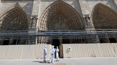 Trabajadores esperan en el exterior de las obras de reconstrucción de la catedral de Notre-Dame en París el 15 de abril de 2022, antes de una visita del presidente francés para conmemorar el tercer aniversario de un incendio que destruyó parcialmente la catedral.