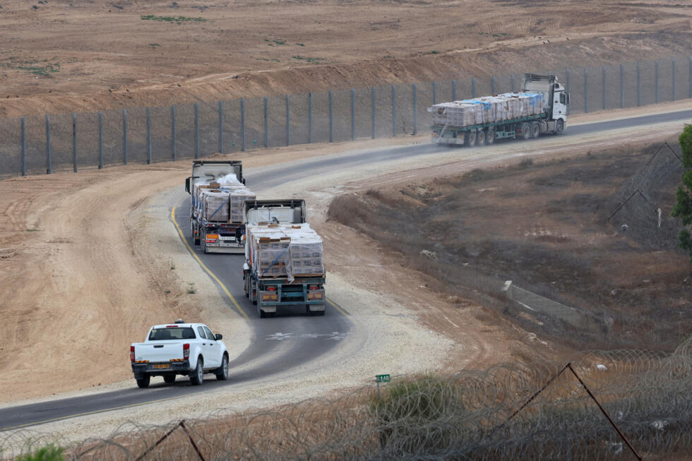 Des camions transportant de l'aide humanitaire destinée aux Palestiniens de Gaza circulent le long de la frontière avec le territoire assiégé, dans le sud d'Israël, le 13 août 2025.