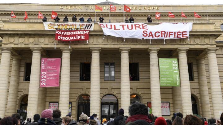 Demonstrators gather as union members hang banners and flags from the balcony of the Odéon theatre in Paris on March 5, 2021, to demand the reopening of cultural establishments in France.