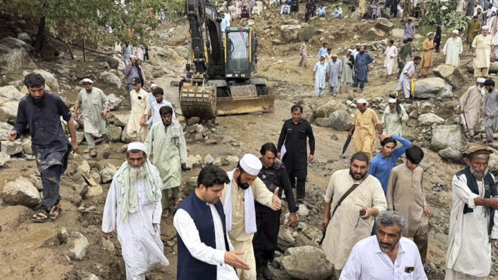 Rescuers and local residents attend a rescue operation at the site of a massive cloudburst led to flash flooding in Salarzai, in Bajaur district, in northwestern Pakistan, on August 15, 2025.