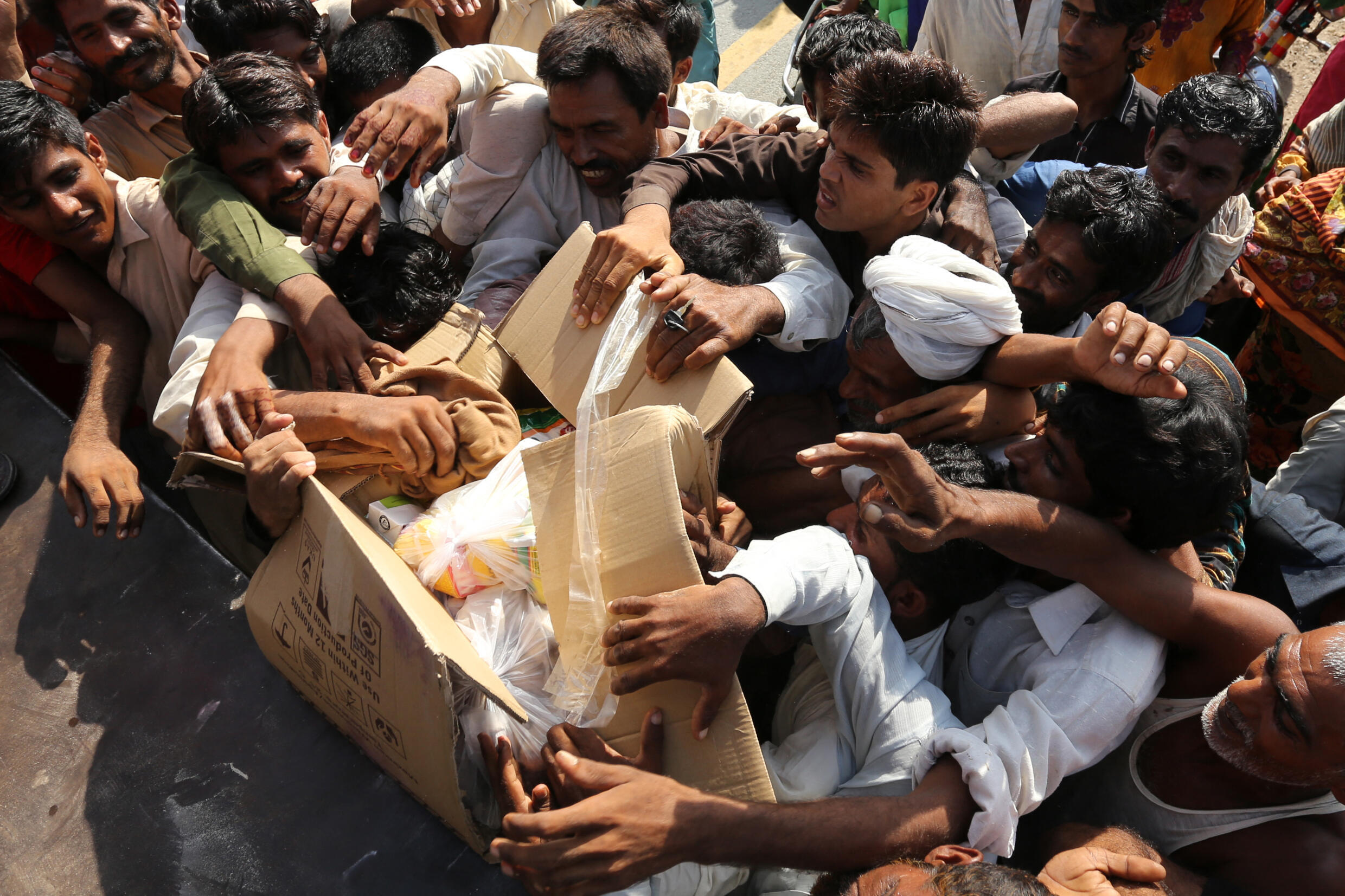 Desplazados del distrito de Dera Ghazi Khan se agarran a bolsas de comida.