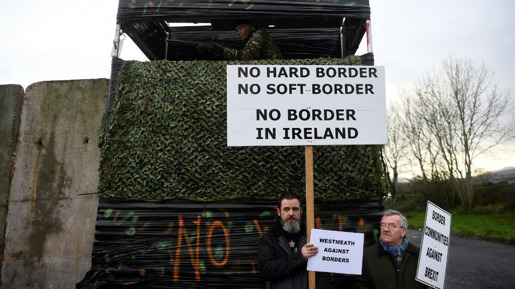 Las personas tienen carteles junto a una barricada fronteriza simulada durante una protesta de activistas contra el Brexit,en Carrickcarnan, Irlanda, el 26 de enero de 2019.