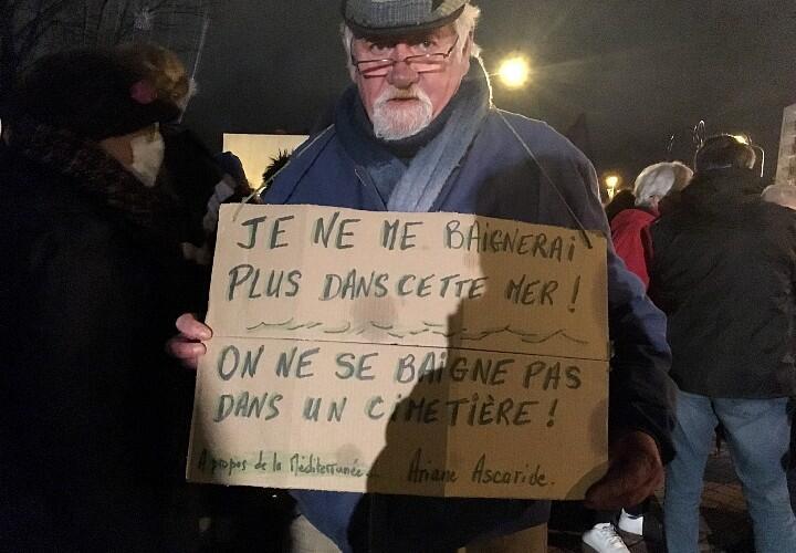 Pascal Lefevre, aktywista z La France insoumise w Calais, podczas hołdu dla 27 migrantów, którzy zginęli w dzielnicy Manche, 25 listopada 2021 r. Można to przeczytać na jego plakacie "Nie kąpałbym się w tym morzu!  Nie kąpiesz się na cmentarzu!"