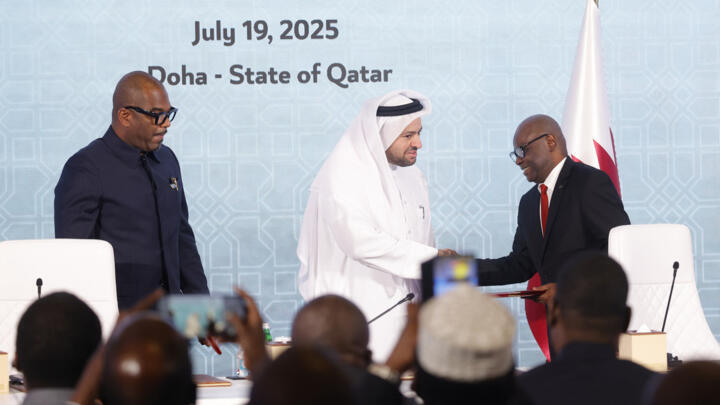 Peace mediator Sumbu Sita Mambu, representative of the Democratic Republic of Congo (L), looks on as Qatar's chief negotiator Mohammed al-Khulaifi (C) shakes hands with Rwanda-backed rebel group M23 e