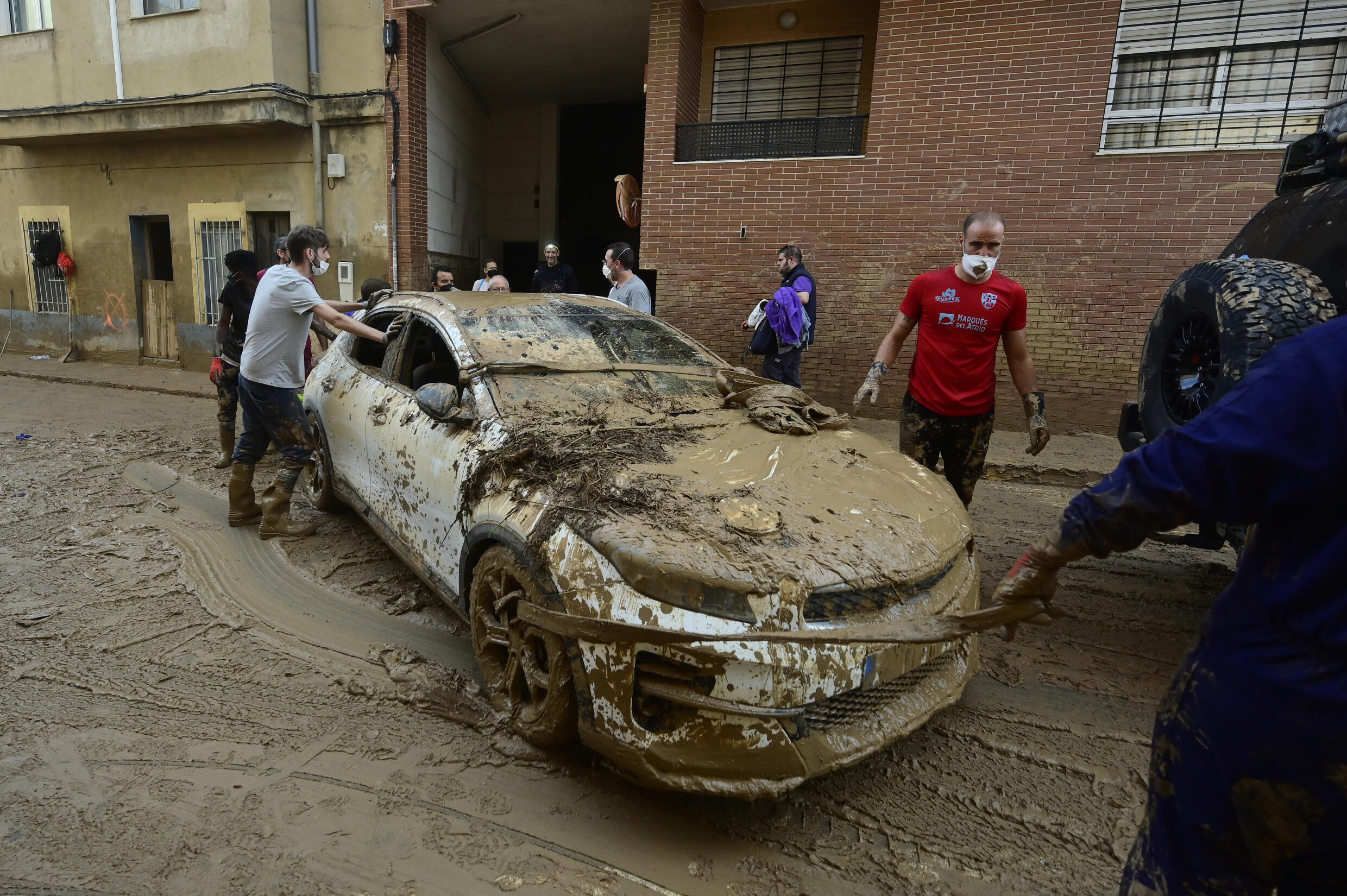 Des habitants tentent de bouger une voiture dans la ville de Massanassa, dans la région de Valence, le 8 novembre 2024