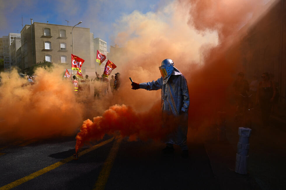 A protester lights flares in Marseille on September 18, 2025, during a day of nationwide strikes called by unions over a proposed national budget that critics say is too austere.