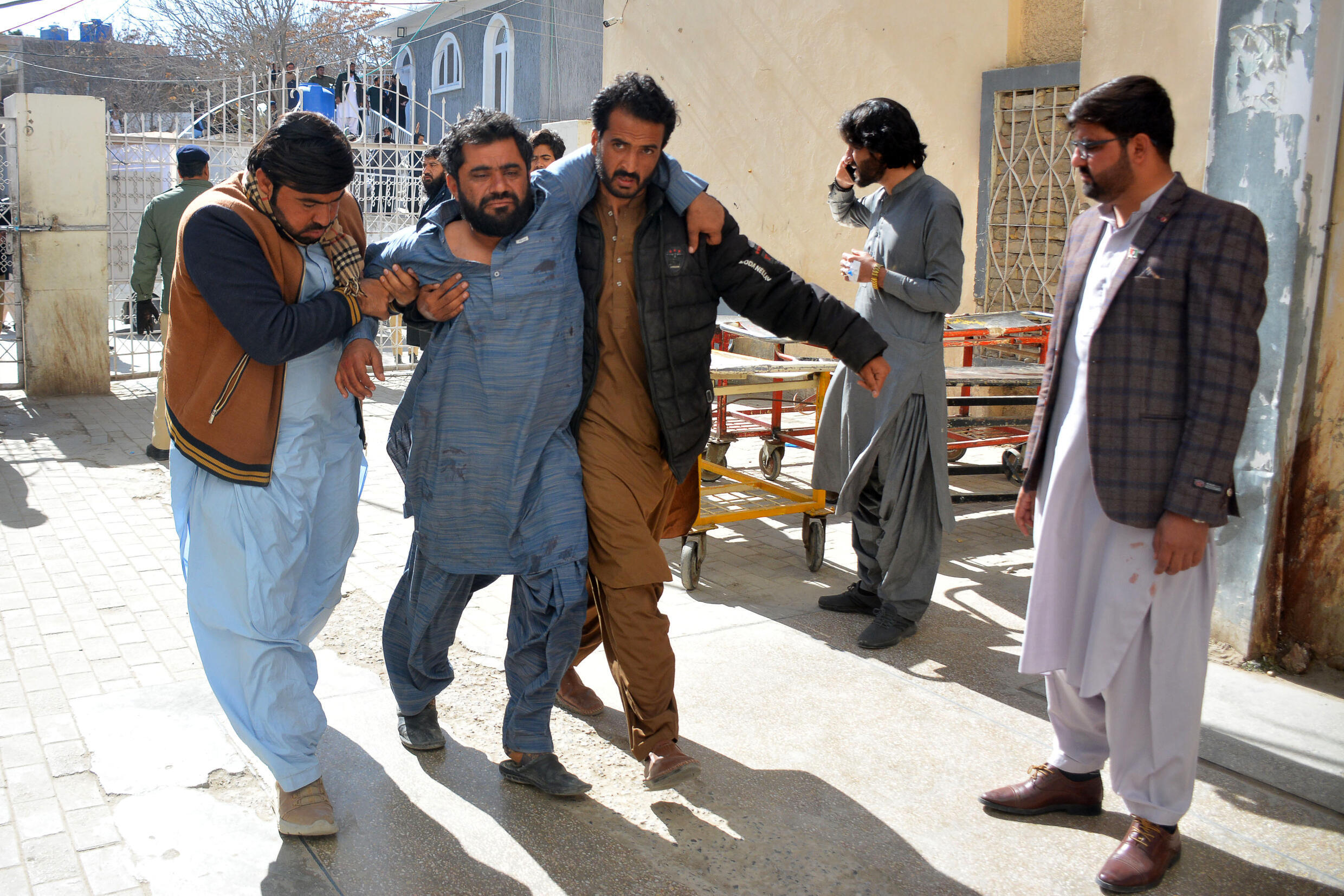 Une victime d'un attentat à la bombe est aidée pour entrer dans un hôpital de Quetta le 7 février 2024. Au moins 28 personnes ont été tuées mercredi dans deux attentats à la bombe distincts devant les bureaux des candidats aux élections dans le sud-ouest du Pakistan