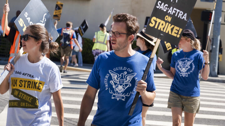 In a show of solidarity, WGA screenwriter Ben Flores joins SAG-AFTRA picketers outside the gates of Warner Bros. studios in Burbank, California, Tuesday, September 26, 2023.