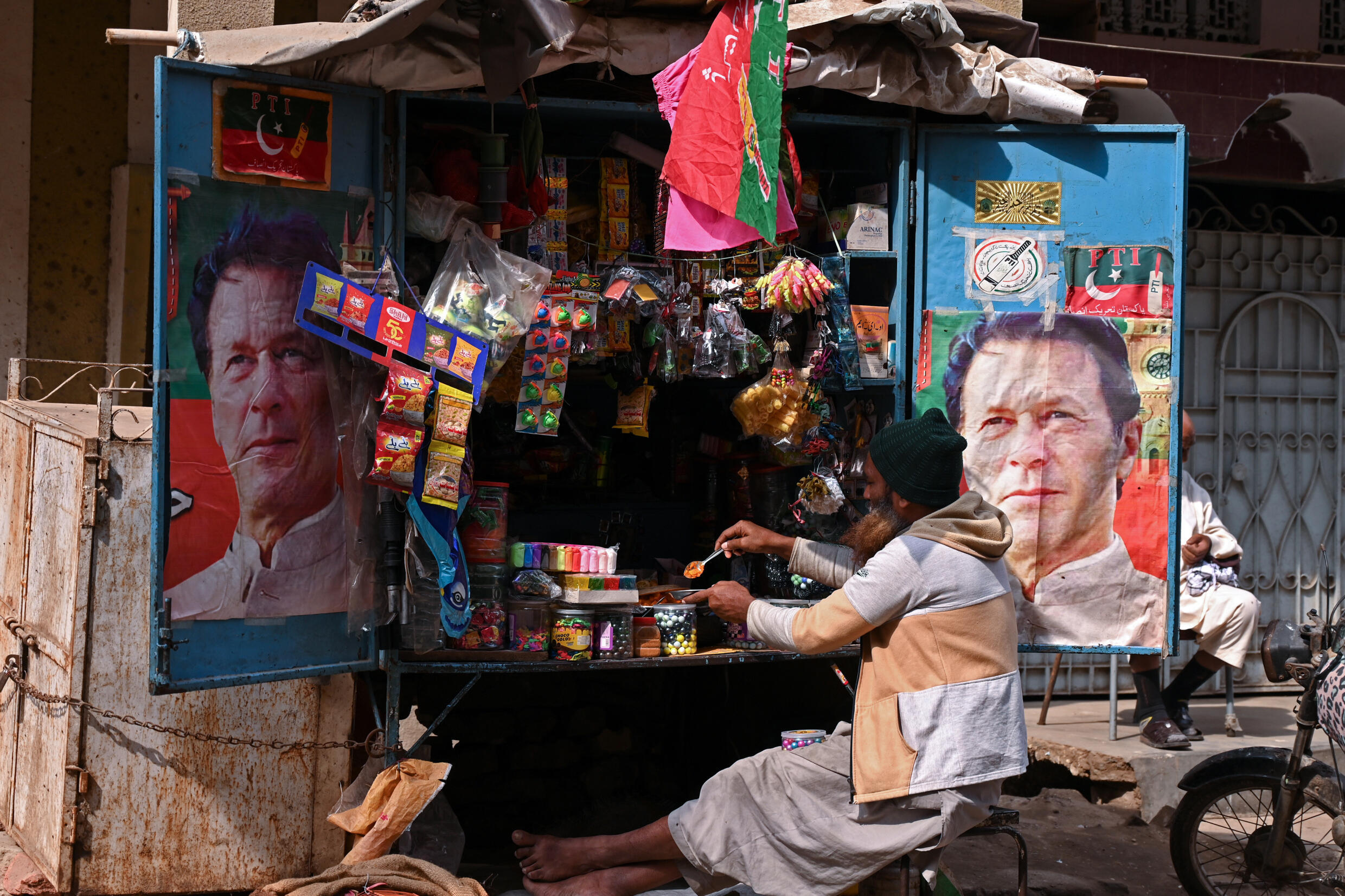 Un vendeur est assis dans son échoppe encadrée par des affiches de l'ancien Premier ministre pakistanais Imran Khan, à Hyderabad, le 29 janvier 2024