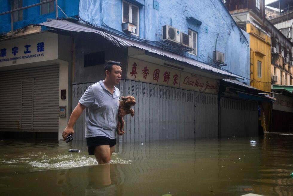 A man carries his dog as he walks through a flooded street during Super Typhoon Ragasa in Macau on September 24, 2025.