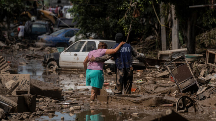 A soldier helps a woman cross a flooded street in Poza Rica, Veracruz state, Mexico on October 12, 2025. 