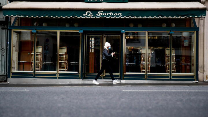 A woman walks past a closed restaurant in Paris as the French government keeps bars and restaurants closed to stem the coronavirus outbreak in France, on January 5, 2021.