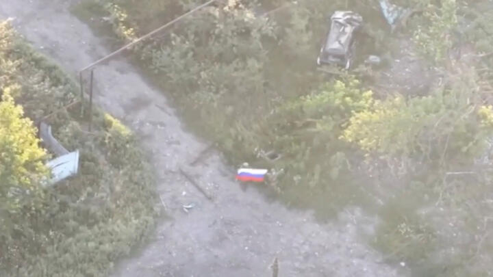 Russian soldiers waving a flag following the capture of Ukraine's Yablunivka settlement in the Donetsk region.