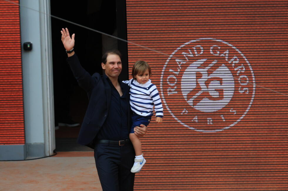 Rafael Nadal quittant le court Philippe-Chatrier de Roland-Garros avec son fils dans les bras.