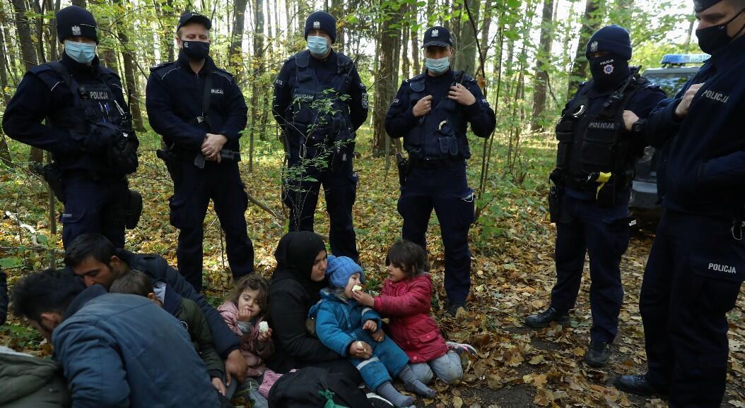 Kobieta emigrująca do Iraku z dziećmi w otoczeniu straży granicznej i funkcjonariuszy policji po przekroczeniu granicy białorusko-polskiej podczas obecnego kryzysu migracyjnego 14 października 2021 r. w Hajnówce w Polsce.