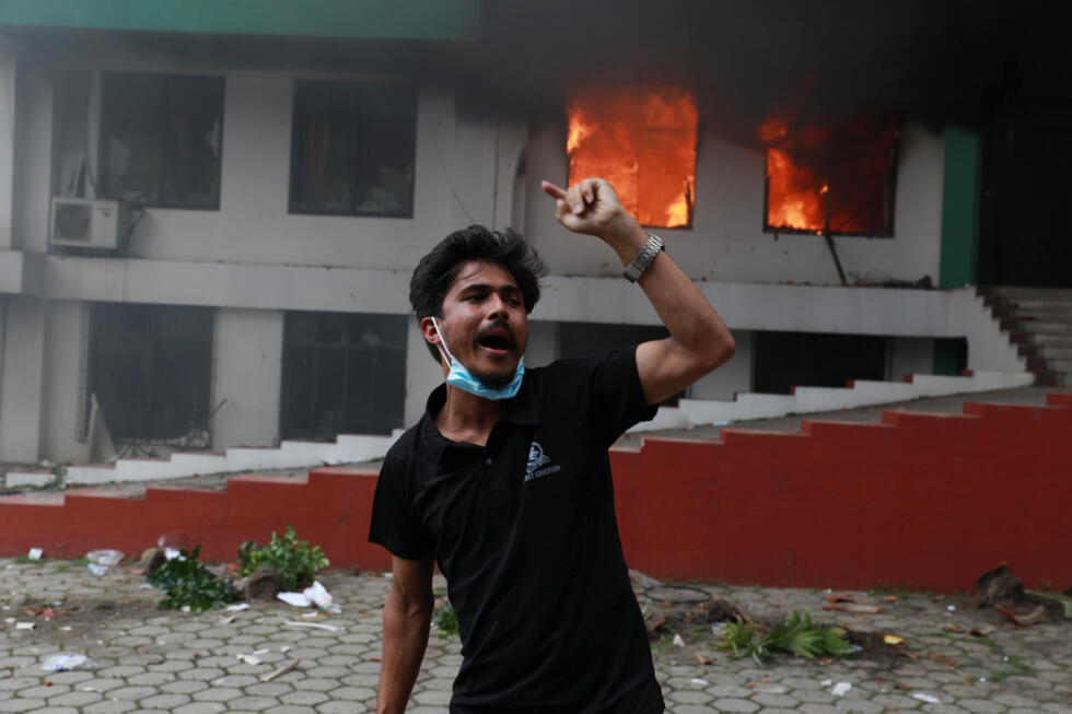 A protester celebrates outside the burning Nepali Congress Party office in Kathmandu.