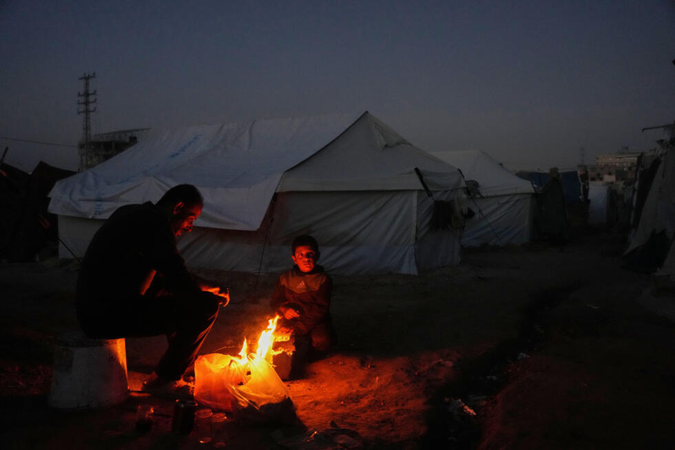 Salah al-Mabhouh, 40 ans, réfugié palestinien, assis près du feu avec son fils Abdul-Razzaq, 8 ans, à côté de leur tente dans le camp d'al-Bureij, dans le centre de la bande de Gaza, le 24 décembre