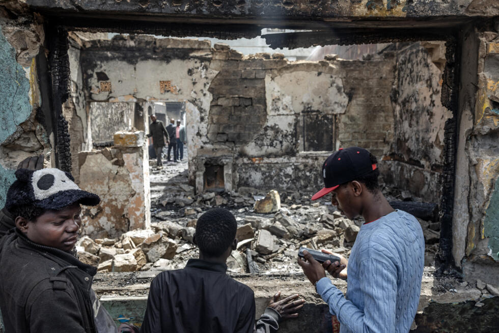 Des résidents évaluent les dégâts dans un bâtiment commercial qui a été vandalisé et incendié lors des manifestations meurtrières à Nairobi, le 26 juin 2025.