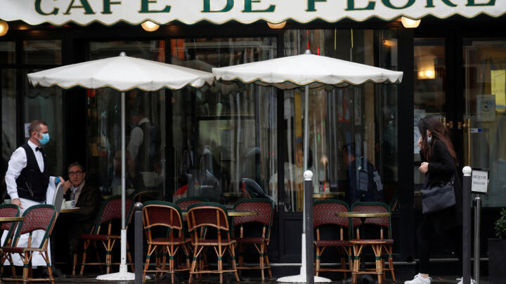 A waiter wearing a protective face mask serves at the Cafe de Flore in Paris, during the announcement of new Covid restrictions by Paris authorities as the Covid-19 outbreak continues in France, October 5, 2020.