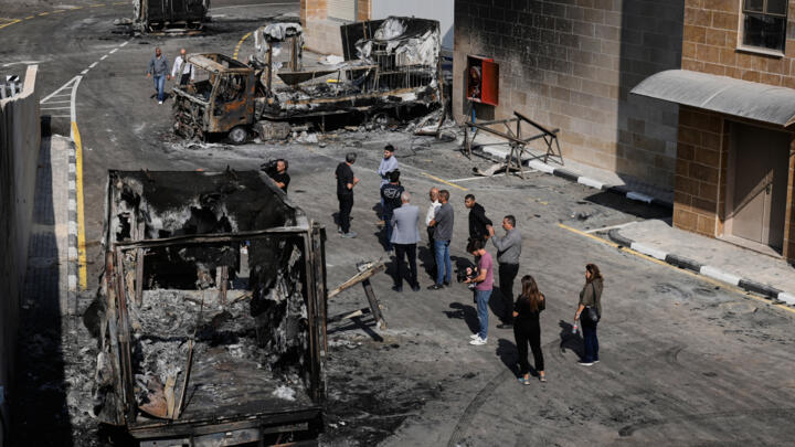 Palestinians and journalists survey damage in an industrial zone following an attack by Israeli settlers the previous day in the West Bank village of Beit Lid, near Tulkarm on November 12, 2025.