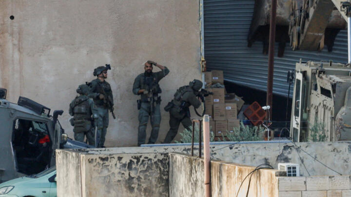Israeli soldiers hold a blanket to cover the scene of a shooting during a raid in Jenin in theWest Bank, on November 27, 2025. 