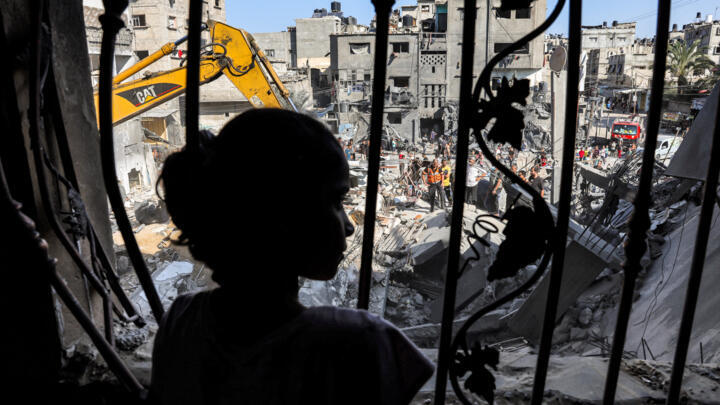 A girl stands behind the metal mesh that covered the window of a building that was hit by Israeli bombardment in Rafah in the southern Gaza Strip on October 31, 2023 amid ongoing battles between Israel and the Palestinian militant group Hamas. 