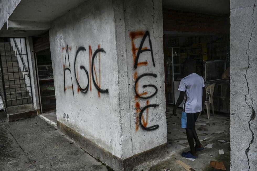 Un niño ingresa a una tienda con grafitis de los paramilitares AGC Autodefensas Gaitanistas de Colombia o Clan del Golfo y la guerrilla del ELN en la vereda La Colonia en la región del bajo río Calima, cerca de la ciudad portuaria de Buenventura, departamento del Valle del Cauca. el 18 de mayo de 2022.