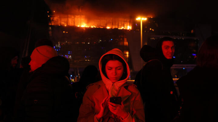 People are seen outside the burning Crocus City Hall concert hall following the shooting incident in Krasnogorsk, outside Moscow, on March 22, 2024. 