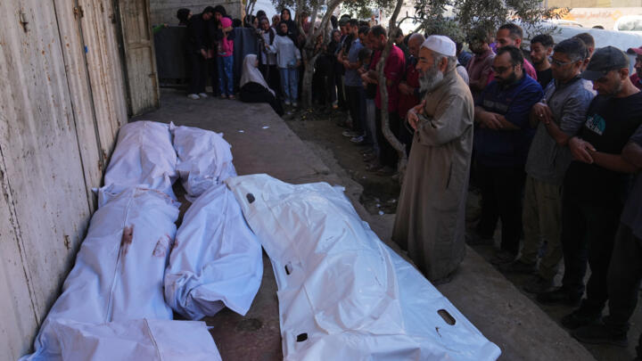 Palestinians pray over the bodies of people who were killed in an Israeli military strike on Sunday, during their funeral at Awda Hospital, in Nuseirat, in the central Gaza Strip.