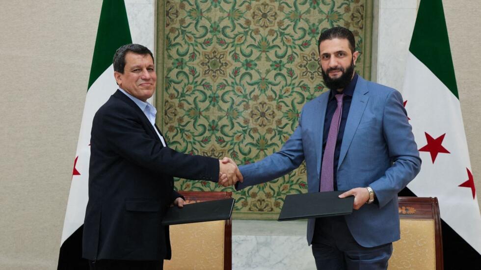 Le président par intérim de la Syrie, Ahmed al-Charaa (à droite), serre la main du commandant en chef des Forces démocratiques syriennes (FDS), Mazloum Abdi, après la signature d'un accord visant à in