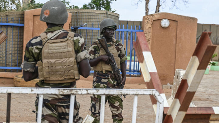 Nigerien soldiers stand guard outside the Niger and French airbases in Niamey as supporters of Niger's National Council for the Safeguard of the Homeland (CNSP) gather on August 27, 2023.
