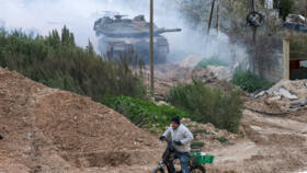 A man rides his bicycle as Israeli tanks enter the Jenin camp for Palestinian refugees in the occupied West Bank, on February 23, 2025.